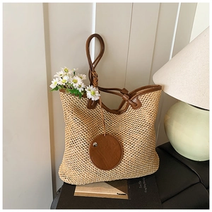 Close-up of handwoven straw tote with brown leather handles and knotted strap detail