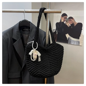 Detail of black hand-woven tote bag with pearl and plush sheep charms on a metal hanger