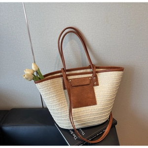 Close-up of woven straw tote bag with brown leather handles on a vintage book