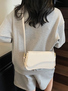 White litchi pattern leather crossbody bag with curved flap and gold hardware on model