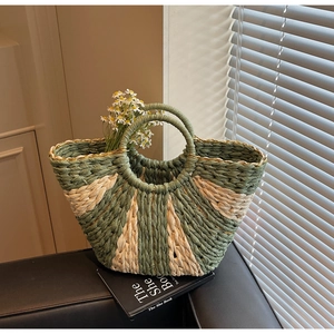 Detail of hand-woven straw bag with green contrast pattern and circular handles