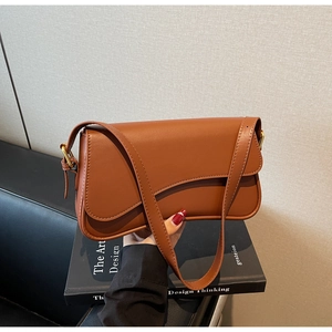 Détail du sac sous l'aisselle marron avec rabat asymétrique et boucles dorées chic