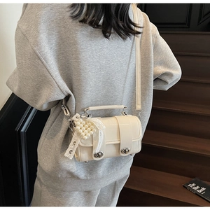 Dettaglio della mini borsa in pelle bianco crema con ciondolo cuore e pizzo bianco