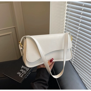 Détail d'un sac à bandoulière blanc minimaliste avec rabat asymétrique et boucles dorées