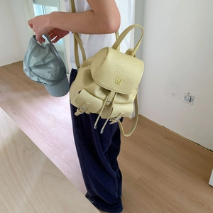Detail of light yellow lychee pattern leather backpack with flap and drawstring closure