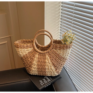 Close-up of contrast woven straw bag with round handle and golden trim detail