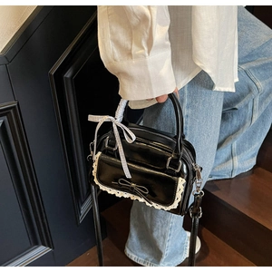 Detail of black bow handbag with white lace trim and blue checkered ribbon on handle