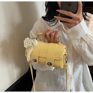 Dettaglio di una borsa a cilindro giallo brillante con fibbie argentate e cuore di perle