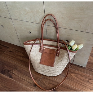Detail of woven straw tote bag with brown leather trim and decorative tulips