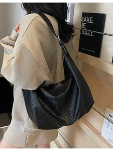 Classic black leather hobo bag with adjustable strap worn by model in minimalist setting