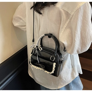 Detail of black bow handbag with lace edges and checkered silk scarf wrapped handle