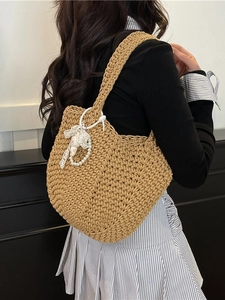 Chic woven tote bag with lace bow and pearl charm shown on model in earth tone style