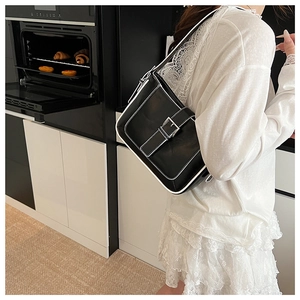 Detail of black crescent shoulder bag with white contrast piping and silver buckle