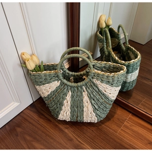 Detail of the woven texture on this green and beige striped straw tote with round handles