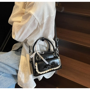 Close-up of a black vintage-style mini bowling bag with white lace trim and bow detailing