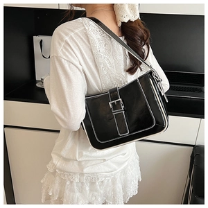 Detail of vintage black shoulder bag with white contrast stitching and oil wax texture