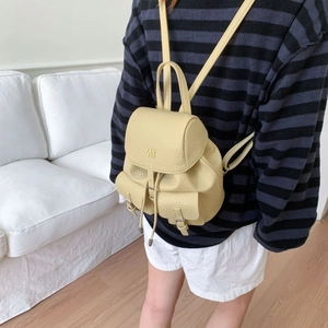 Lifestyle shot of a pale yellow mini backpack with premium pebble leather and gold logo