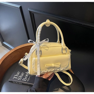 Detail of yellow bow shoulder bag with lace flap and blue plaid ribbon on the handle