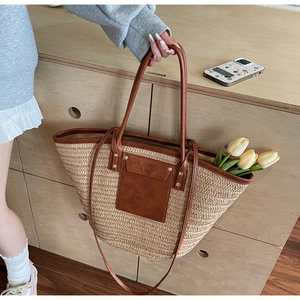 Detail of woven straw tote bag with brown leather pocket and handles for beach