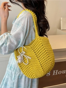 Handmade yellow knit tote bag with rabbit charm worn by model in casual setting