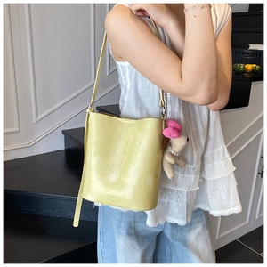 Detail of yellow bucket bag with SNML text and cute teddy bear plush charm