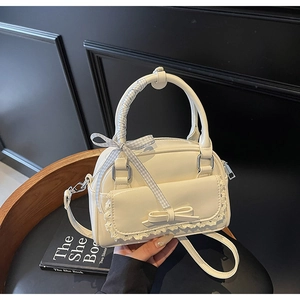 Detail of cream bow handbag with lace trim, plaid ribbon handle and silver hardware