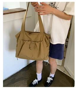 Detail der khakifarbenen großen Tragetasche mit Kordelzugtasche am Model getragen