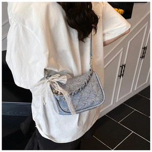 Détail du sac à chaîne bleu clair avec strass et nœud en dentelle sur un modèle