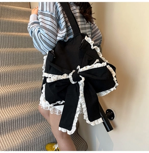 Dettaglio del bordo in pizzo bianco e del grande fiocco sulla borsa in tela nera