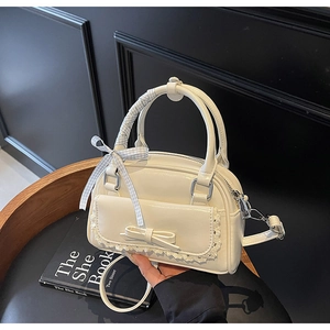 Detail of cream white bow handbag with lace trim and blue checkered ribbon handle