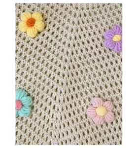 Close-up of beige crochet tote bag featuring colorful 3D knitted flower details