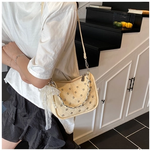 Détail du sac à bandoulière blanc cassé avec texture tissée, rivets et nœud en dentelle