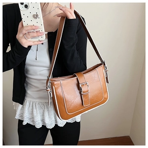 Detail of caramel brown PU leather crescent bag with white contrast stitching and buckle