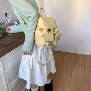 Detail view of cream leather backpack with lychee texture and flip lock pockets