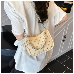 Détail du sac hobo crème avec clous argentés, chaîne et breloque perle en dentelle