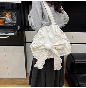 Borsa tote in tela bianca con grande fiocco e pizzo indossata a spalla