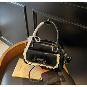 Close-up of black retro bow handbag with lace trim detail and ribbon-wrapped handle