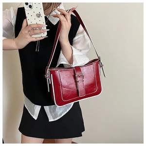 Detail of dark red crescent shoulder bag with white contrast piping and metal buckle