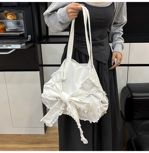 Dettaglio della borsa tote in tela bianca con grande fiocco e rifiniture in pizzo