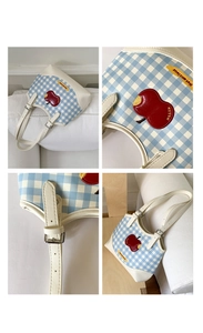 Close-up of blue gingham shoulder bag with red apple patch and Not Anxious label detail