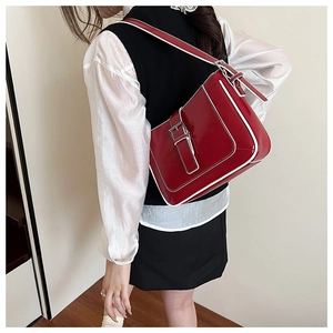 Detail of red patent leather shoulder bag featuring white contrast stitching and silver buckle