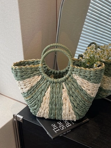 Green and beige striped woven straw tote bag with round handles for beach summer vacations