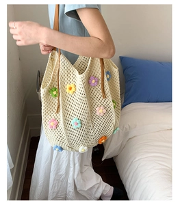 Detail of hand-woven cream tote bag with colorful 3D floral accents and leather straps