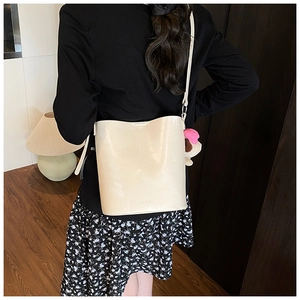 Detail of cream white bucket bag with leather texture and pink plush bear charm