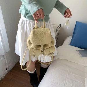 Close-up of yellow pebbled leather mini backpack featuring drawstrings and metal buckles