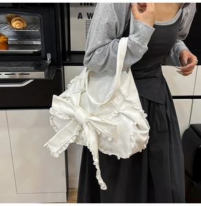 Dettaglio borsa tote in tela bianca con maxi fiocco e bordo in pizzo raffinato