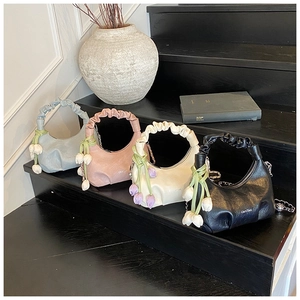 Detailed view of four colorful croissant bags with tulip charms on wooden stairs