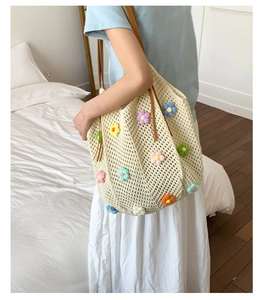 Detailed close-up of colorful 3D knitted flowers on a cream crochet tote bag
