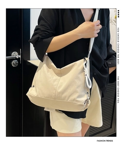 Détail du sac bandoulière beige de forme croissant avec bandoulière large et boucle