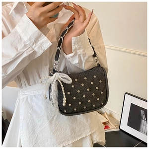Détail d'un sac bandoulière gris matelassé avec nœud en dentelle et perles sur modèle